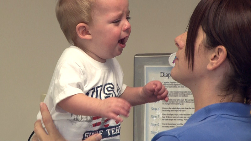 A staff member holds a crying toddler