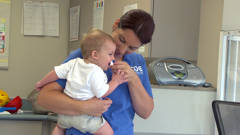 A staff member holds a laughing toddler after consoling him when he was upset