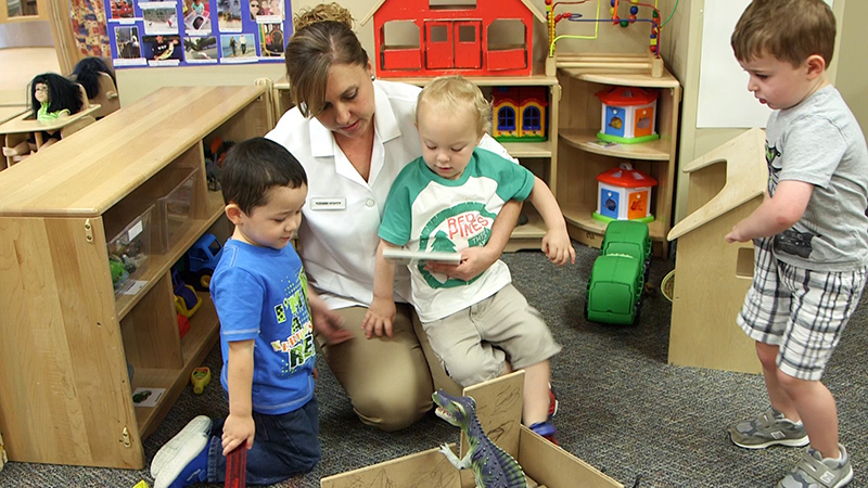 caregiver and toddlers play with engaging toys