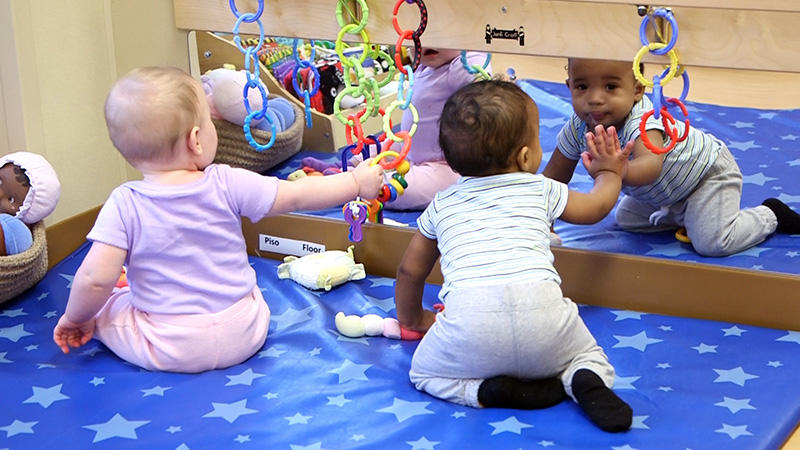 infants playing with a mirror