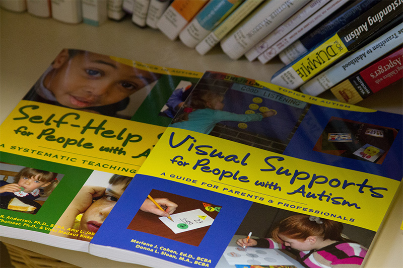 A book display shows the center supports all learners with titles like "Visual Supports for People with Autism"