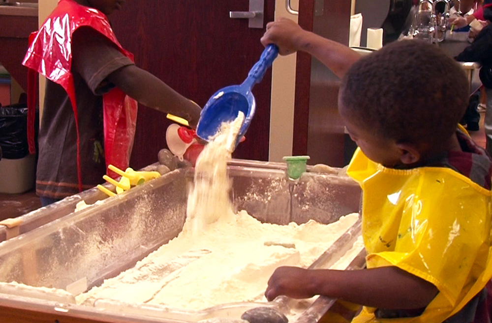 Two boys learn while playing in a sensory table